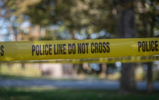 Police tape strung over the outdoor scene of an active shooter scenario